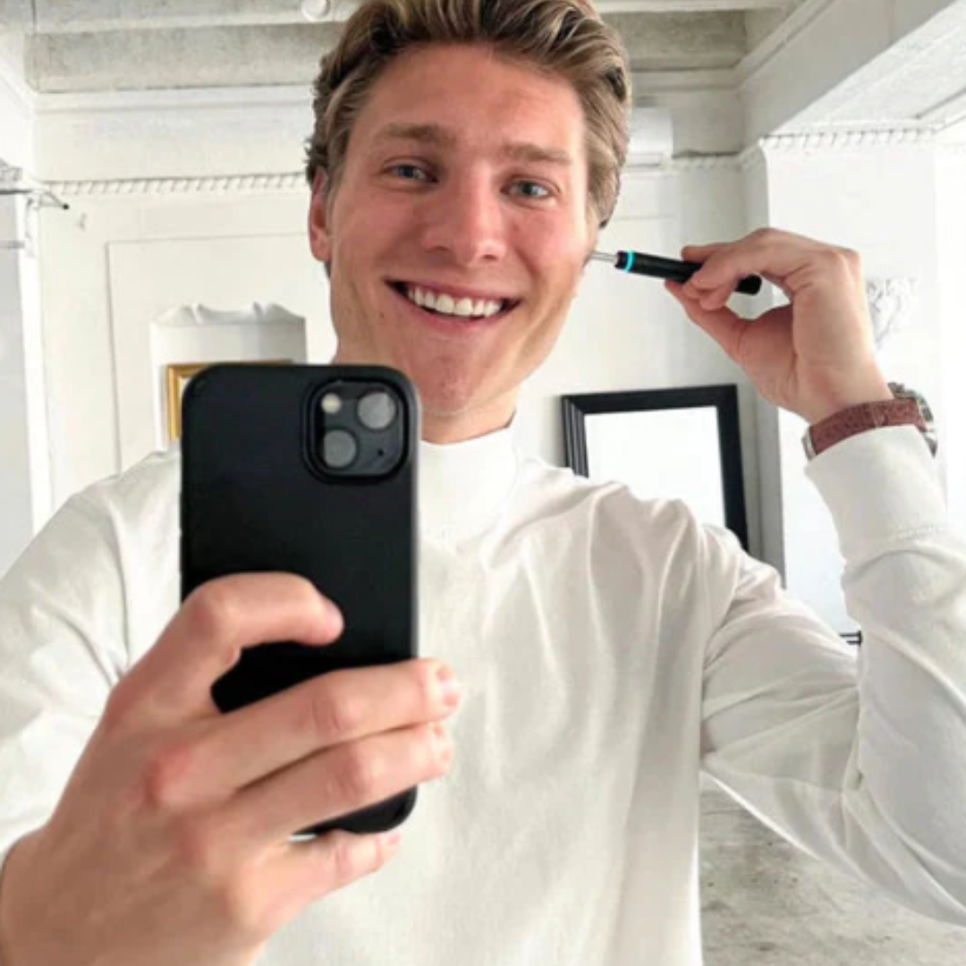 Person uses WaxClean ear wax cleaner with HD camera and sees real-time image of ear canal via smartphone.